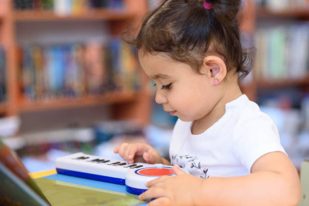 happy child little girl pianist plays on a toy piano. - toddler music asian ethnicity child imagens e fotografias de stock