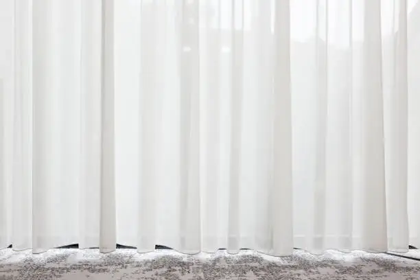 Photo of Long, white, semy see-through curtain hanging in the window