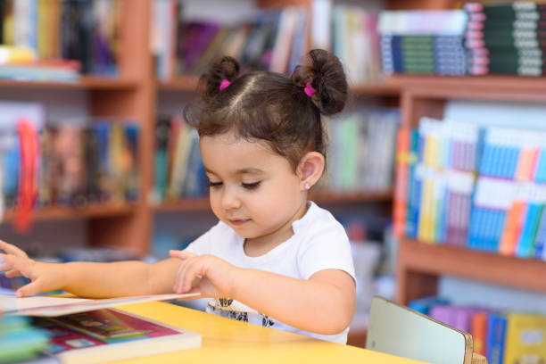 istock Happy child little girl reading a book. 1154573392