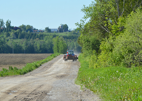 Farm tractor driving down the road towing an implement of husbandry