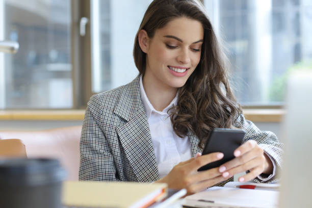 istock Young smiling business woman using smartphone near computer in office. 1154579602