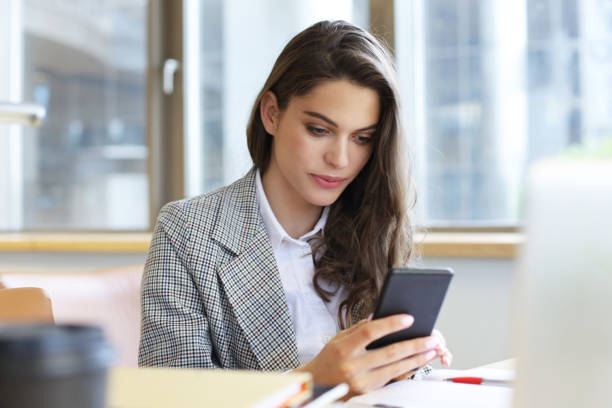 istock Young smiling business woman using smartphone near computer in office. 1154579760