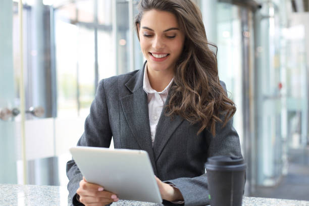 istock Young smiling businesswoman in office working on digital tablet. 1154579880