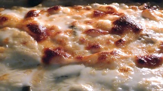 detail of a baking pizza with cheese boiling. Close up view of cheese and sauce bubbles.