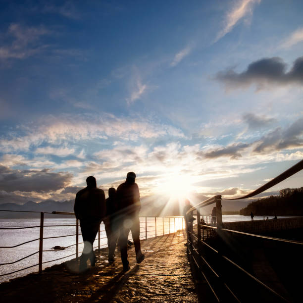 silhouetted  people walking on street over sunset sky with sunbeam in Antalya harbor, Turkey