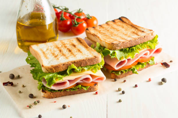 nahaufnahme eines club-sandwiches. sandwich mit fleisch, schinken, salami, salat, gemüse, salat, tomaten, zwiebeln und senf auf einem frisch geschnittenen roggenbrot auf holzgrund. oliven hintergrund. - sandwich turkey gourmet fast food stock-fotos und bilder