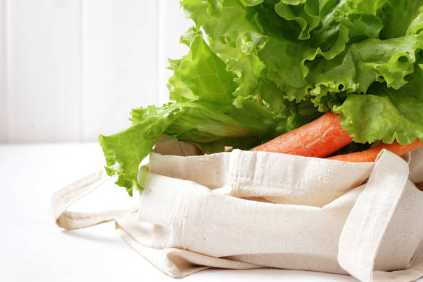 verduras frescas hojas de ensalada de lechuga y casa de zanahoria jardín en linnen bolsa de compras en la mesa blanca contra la pared de madera blanca - leafes fotografías e imágenes de stock