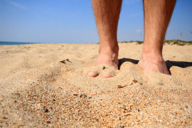 istock Lonely man standing alone on the beach. Feets  in sand 1154593249