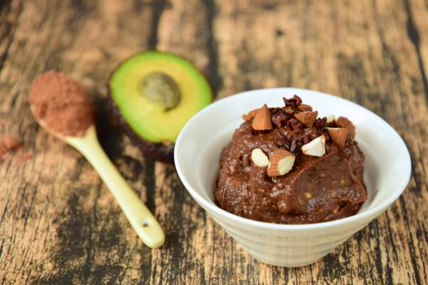 Délicieuse mousse au chocolat Vegan avec banane, avocat, cacao en poudre et sirop d’érable. Garnir de noix d’amande et de plumes de cacao - Photo