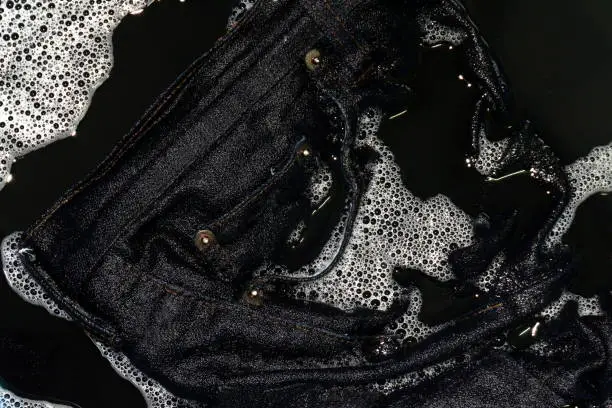 Photo of Jeans blue dark soak in sponge washing and wet in sponge water dirty black, Colored jeans clothes