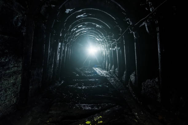 istock Dark abandoned coal mine with rusty miner stands 1154596617