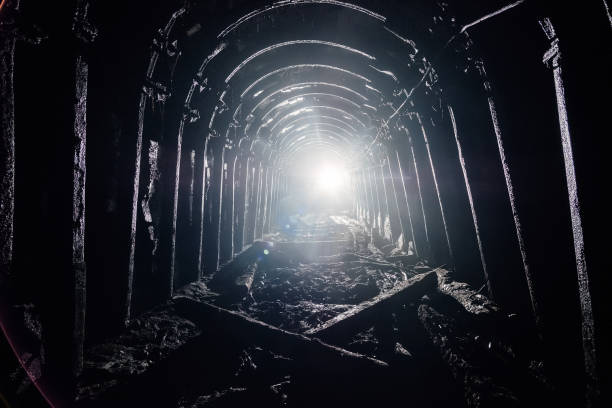 Group of men working at a mine looking at the rock in a dark tunnel- mining concepts