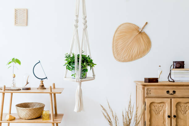istock Stylish and minimalistic boho interior with design and handmade macrame shelf planter hanger for indoor plants, wooden furnitures, elegant accessories ,rattan basket and leaf. Cozy home decor. 1154596868