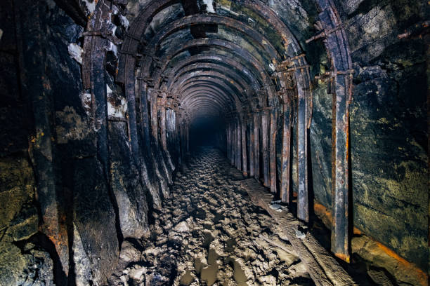 istock Dark abandoned coal mine with rusty miner stands 1154597541