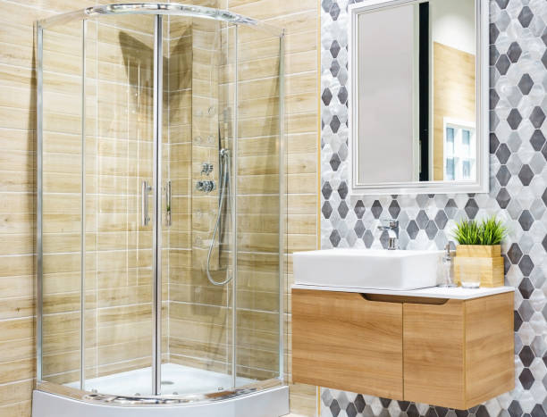 istock Spacious and bright modern bathroom interior with white walls, a shower cabin with glass wall, a toilet and faucet sink 1154597802