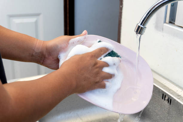 istock Man washing dishes in kitchen sink 1154598136
