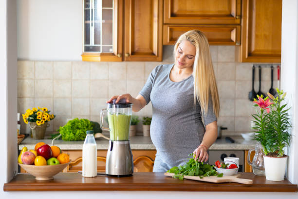 istock Pregnant woman using blender for making healthy drink 1154603348