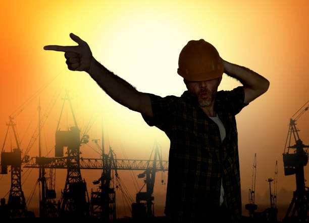 silhouette of workman dancing happy emulating with hard hat pop star pose celebrating workday is over isolated on harbour cranes background as cheerful worker on friday - employ imagens e fotografias de stock