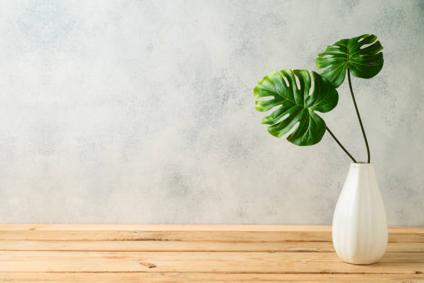 istock Tropical leaves in vase on wooden table 1154606267