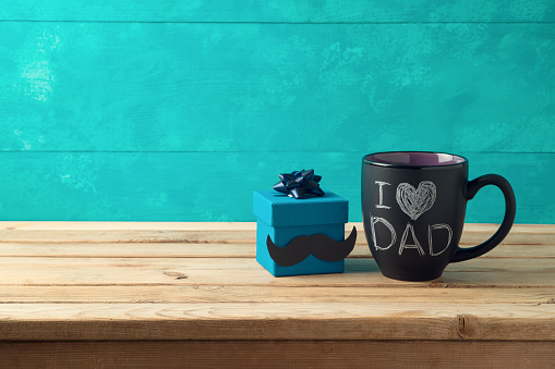Happy Father's day concept with coffee mug and gift box over wooden background