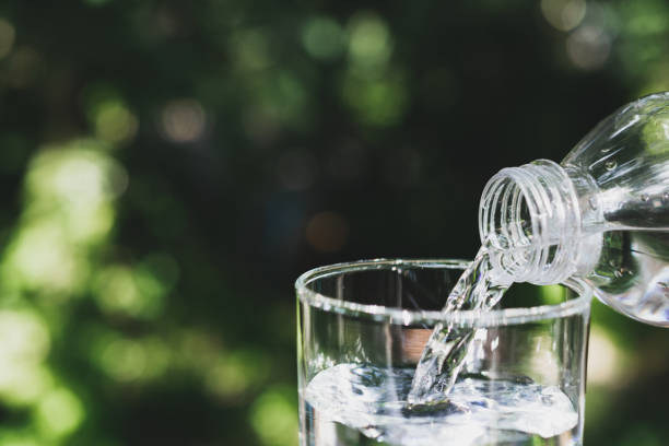 istock Hand holding water bottle in nature background. 1154607840