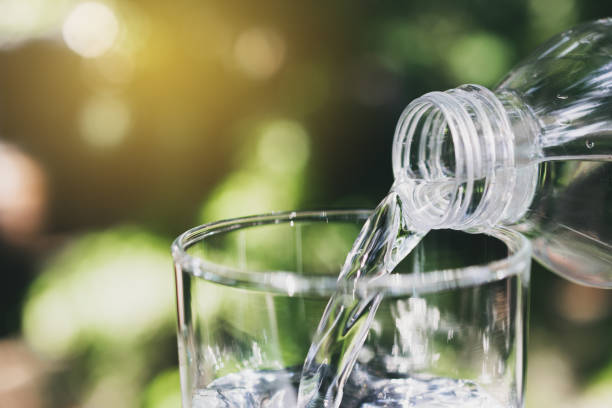 istock Hand holding water bottle in nature background. 1154607884