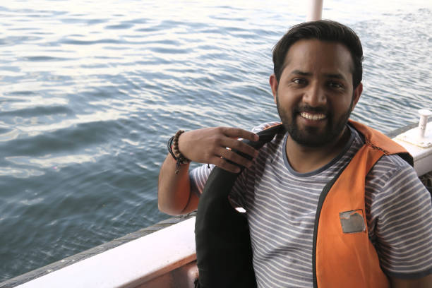 image of happy hindu indian man passenger in tourist cruise boat wearing lifejacket, orange life jacket buoyancy aid lake pichola, by taj lake palace, lake pichola udaipur, tourist boat man smiling, summer holiday vacation in udaipur, cruising lake views - motorboating sailing life jacket lake imagens e fotografias de stock