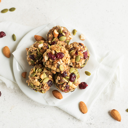 Energy granola bites with nuts, seeds, dry cranberries and honey - vegan vegetarian raw organic snack granola bites on white background, copy space.