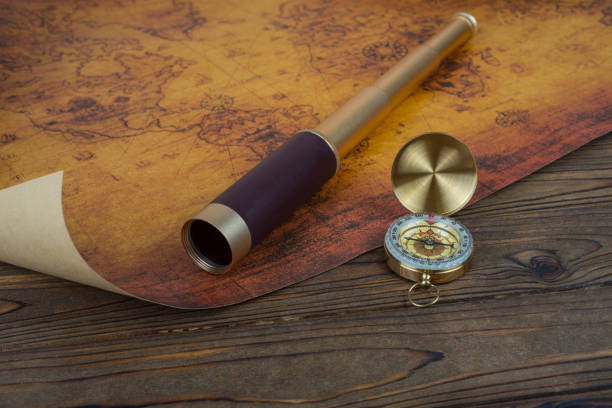 Spyglass, compass and old map on wooden background. Travel concept, hike.