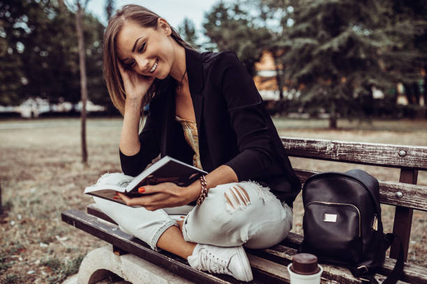 istock Woman sitting at the park bench and reading a book 1154625863