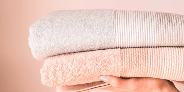 istock Fresh towels on woman's hand on pink background 1154628169