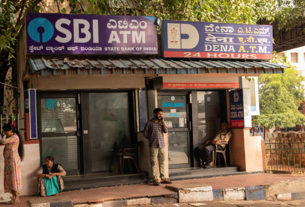 BANGALORE INDIA June 3, 2019 :People sitting infront of the SBI ATM and DENA bank ATM's at bangalore railway station. BANGALORE INDIA June 3, 2019 :People sitting in front of the SBI ATM and DENA bank ATM's at Bangalore railway station atm photos stock pictures, royalty-free photos & images