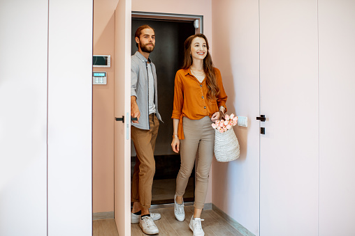 Beautiful young couple coming home, walking together in the pink corridor of the modern apartment