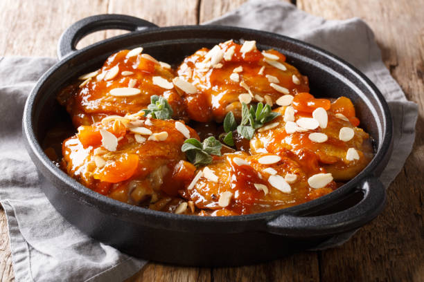 rustic style baked chicken thighs with dried apricots and almond flakes close-up in a frying pan. horizontal - main course imagens e fotografias de stock