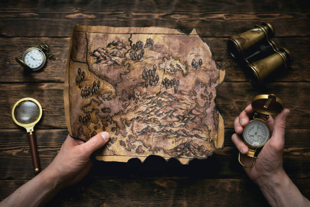 Treasure map. Old map in man adventurer hands on a brown table background. Treasure hunt concept. treasure chest photos stock pictures, royalty-free photos & images
