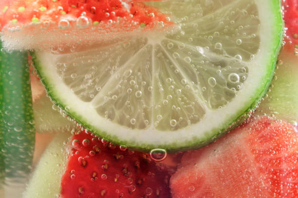 refrescante agua cristalina de frutas de fresas y lima en una taza de vidrio de cerca, de fondo. - raspberry soda fotografías e imágenes de stock