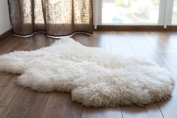 piel de oveja en el suelo laminado en la habitación. lugar acogedor cerca de la ventana - tapete fotografías e imágenes de stock