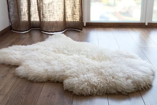 Sheep skin on the laminate floor in the room. Cozy place near the window