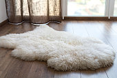 Sheep skin on the laminate floor in the room. Cozy place near the window