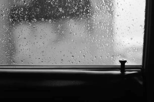 Photo of Car glass with drops of rain with copy space. Atmospheric monochrome background with raindrops. Droplets on automobile window close-up. Locked in car in rainy weather. Inside car during rainstorm.