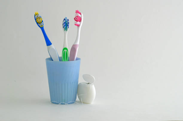 istock Three toothbrush in a cup and a floss for cleaning teeth on a white background. space for text and advertising. 1154645968
