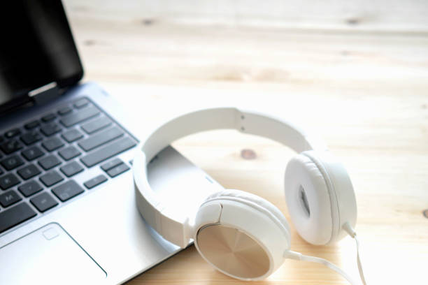istock White headphone and laptop computer on wooden background 1154647874