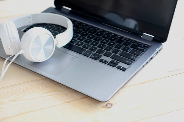 istock White headphone and laptop computer on wooden background 1154647938