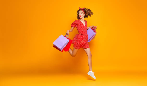 concept of shopping purchases and sales of happy young girl with packages  on yellow background concept of shopping purchases and sales of happy young girl with packages in red dress on yellow background red dress photos stock pictures, royalty-free photos & images