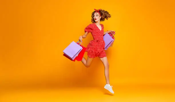 Photo of concept of shopping purchases and sales of happy young girl with packages  on yellow background