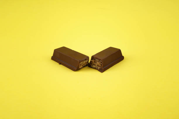 istock Broken bar of dark chocolate on yellow background 1154649424