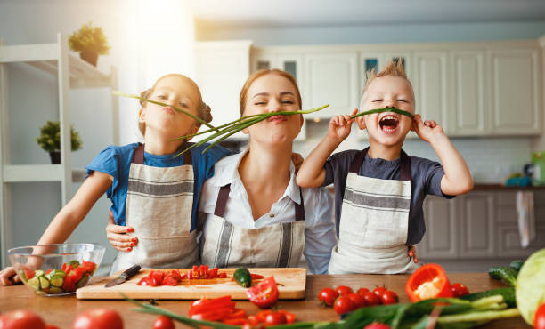 madre con niños preparando ensalada de verduras - sentarse a comer fotos fotografías e imágenes de stock
