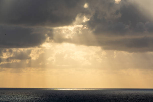 istock Dramatic sunset over sea water with gray clouds and sun lights 1154650496