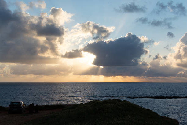 istock Dramatic sunset over sea water with gray clouds and sun lights 1154650509