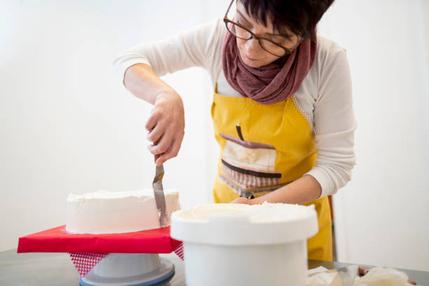 istock Professional confectioner covering a cake with icing 1154651431